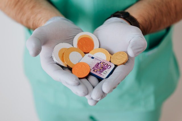 Doctor wearing gloves holding a sum of cash and coins